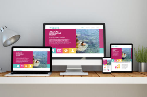 workplace with fresh responsive website on devices A computer, laptop, smartphone and tablet on a desktop workspace with responsive website on screen. 3d rendering. All screen graphics are made up.